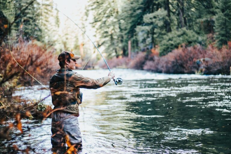 An OWAA member stands in a river and casts his fishing line